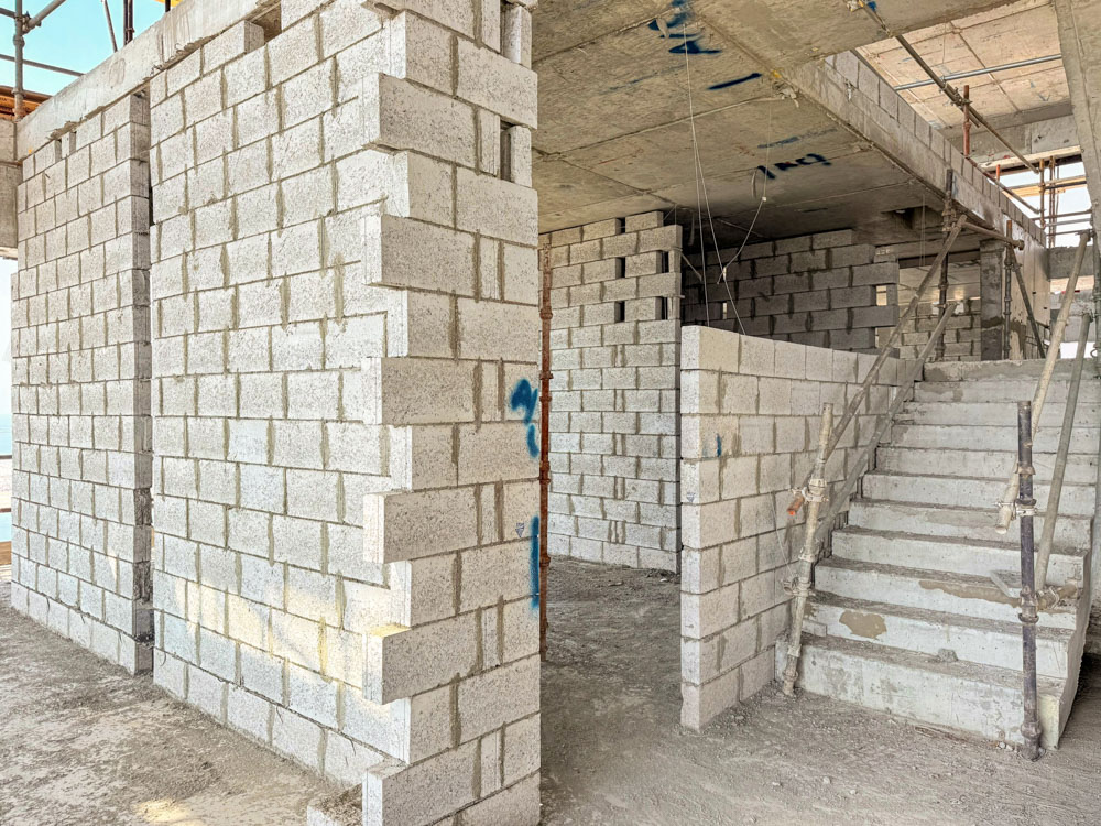 Beach Walk Iii By Imtiaz Construction site showing unfinished walls made of concrete blocks and a staircase under development.